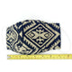 A fabric face mask with a black and beige geometric pattern lies flat on a white surface. A measuring tape below shows a length of approximately 19 centimeters.
