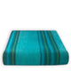 Machay baby alpaca wool blanket – a folded turquoise blanket with dark green and blue stripes is lying flat against a plain white background, showcasing its soft, textured fabric