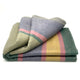 Guagua baby alpaca wool blanket – a folded, multi-colored wool blanket with horizontal stripes in pale green, pink, yellow, and gray, lies neatly displayed against a plain white background