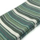 Urauco baby alpaca wool blanket – a folded fabric displays wavy, horizontal stripes in shades of green, teal, and white, suggesting a soft texture suitable for textiles or upholstery. The background is plain white