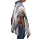 Person wearing a hooded, patterned poncho over a red shirt and blue jeans, standing against a plain white background.
