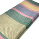 Guagua baby alpaca wool blanket – a folded, multi-colored fabric with wide horizontal stripes in green, pink, yellow, and lavender lies on a plain white surface, showcasing a smooth, woven texture