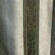 A fabric features vertical green stripes with intricate diamond patterns, surrounded by lighter gray textured stripes, creating a repetitive and symmetrical design.