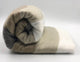Mogato baby alpaca wool blanket – a rolled-up blanket with alternating cream, beige, and gray stripes lies on a flat surface against a plain background