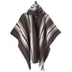 A wool poncho with a hood drapes downward, featuring black, white, and brown stripes in an alternating pattern. It hangs against a plain white background.