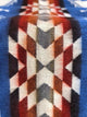 A textile displays a geometric pattern of interlocking chevrons in red, orange, gray, and white, bordered by blue on its sides, creating a vibrant visual effect.