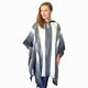 A person is wearing a black and white poncho with geometric patterns, standing against a plain white background, looking to their left.