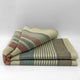 Suropata baby alpaca wool blanket – a folded wool blanket with green, red, and beige stripes, rests on a plain white surface, creating a cozy and simple appearance