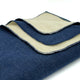 A neatly folded, dual-layered fabric, with a dark blue outer side and a light beige inner side, rests on a bright surface, showcasing its textured appearance and stitched edges.