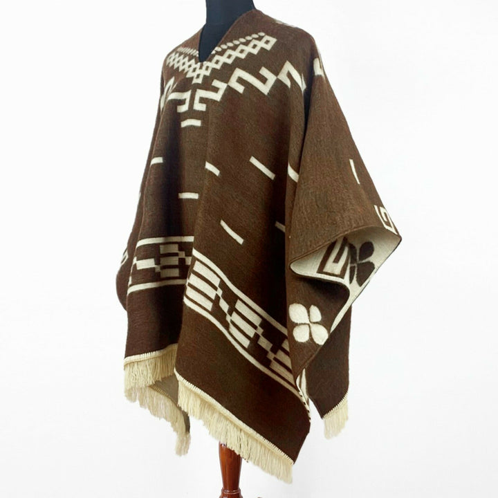 Clint Eastwood alpaca wool poncho – a brown poncho with white geometric patterns and fringe edges is displayed on a mannequin, against a plain background, showcasing traditional design elements and craftsmanship