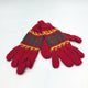Red knitted gloves with green and yellow decorative patterns lie flat against a plain white background.