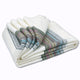 Sigchos baby alpaca wool blanket – a folded, cream-colored blanket with multicolored striped edges lies on a plain, white background. The stripes feature green, blue, pink, and gray hues