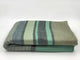 Saquisili baby alpaca wool blanket – a folded woolen blanket features horizontal stripes in various shades of green and gray, resting on a plain white background