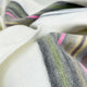 Sigchos baby alpaca wool blanket – a close-up of a soft, folded fabric featuring colorful stripes of pink, green, and gray against a white background, creating a cozy and textured appearance