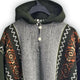 Llama Wool Hooded Poncho – a knitted poncho hangs on a black hanger. It features a grey front with two buttons and patterned sleeves in brown and white geometric designs against a dark background