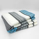 Aychapicho baby alpaca wool blanket – a neatly folded, striped blanket featuring white, gray, and blue colors lies on a white surface, showcasing its soft texture and evenly spaced lines for a clean presentation