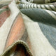 Suropata baby alpaca wool blanket – a wool blanket featuring multi-colored stripes including orange, green, and beige, is casually draped and folded, giving it a soft, textured appearance