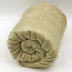 Llullalo baby alpaca wool blanket – a soft, beige blanket is neatly rolled up, resting on a smooth, neutral-colored surface, suggesting a calm, minimalist setting