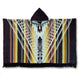 Shakai alpaca wool hooded poncho – hooded poncho showcases intricate geometric patterns in brown, yellow, black, and white hues, incorporating stripes and zigzags. Fringed edges accentuate the textile's bold design, laid flat against a white backdrop