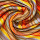 Cumanda baby alpaca wool blanket – a multicolored, striped fabric swirls in a circular pattern, showcasing blended shades of orange, yellow, blue, and brown in a detailed, woven texture