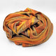 Cumanda baby alpaca wool blanket – a colorful, striped blanket is loosely folded, displaying warm hues of orange, brown, and yellow, set against a plain white background