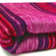 Cayetana baby alpaca wool blanket – a folded, multicolored woolen blanket with vibrant pink, red, and purple stripes, rests neatly on a white surface, showcasing its soft, textured fabric