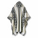 A poncho with a hood features a black and white geometric diamond pattern. It hangs freely, displaying its intricate design on a plain white background.