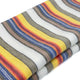 Guayan baby alpaca wool blanket – a folded piece of fabric displays multicolored horizontal stripes in white, yellow, blue, red, and gray, creating a vibrant pattern