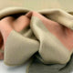 Tilivi baby alpaca wool blanket – a soft, multi-colored fabric is draped casually, featuring hues of beige, pink, and green, creating a gentle, cozy appearance on a smooth, light background