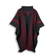 Llama Wool Hooded Poncho – a black woven poncho with geometric red patterns and fringed edges hangs against a plain white background