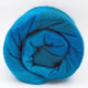 Cajabamba alpaca wool blanket – a tightly wound roll of vibrant blue wool, appearing soft and textured, placed in a simple white background