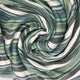 Urauco baby alpaca wool blanket – striped fabric swirls into soft folds. The pattern features varying shades of green, blue, and cream. The texture appears smooth and supple, suggesting a cozy, inviting material