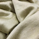 Llullalo baby alpaca wool blanket – a soft, beige fabric, appears rumpled and textured, fills the frame, suggesting warmth and comfort in a close-up view