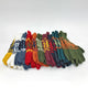 Colorful knitted gloves are neatly arranged in rows, featuring intricate patterns. The gloves display various hues including red, green, blue, orange, and white, set against a plain background.