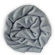 Suncamal baby alpaca wool blanket – a soft, tightly rolled light gray knitted fabric lies against a plain white background, highlighting its texture and woolly appearance