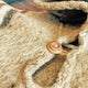 A close-up of a woolen garment features a round, wooden button, partially fastened on textured fabric, set in a warm, softly lit environment.