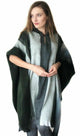 A person stands with hands clasped, wearing a black and gray striped poncho, against a plain white background.