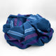Tamboloma baby alpaca wool blanket – a crumpled blue fabric with purple and blue stripes rests on a plain white background, forming soft folds and layers