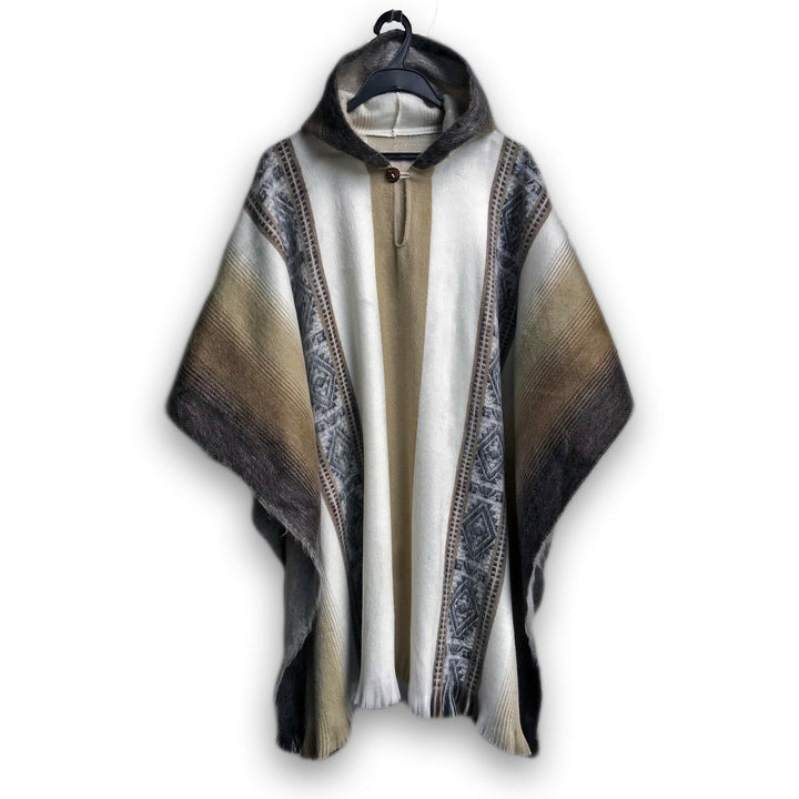 A wool poncho with a hood hangs on a black hanger. The design features earthy tones with geometric patterns and wide vertical stripes, set against a plain white background.