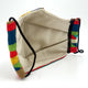 Face mask with a beige interior and colorful woven edges featuring red, blue, green, and yellow sections. Black elastic ear loops are attached. The background is white and minimalist.