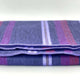 Punguloma baby alpaca wool blanket – a folded purple woolen blanket with subtle red and lavender stripes lies on a smooth, light surface, neatly arranged, showcasing its soft texture in a minimalist setting