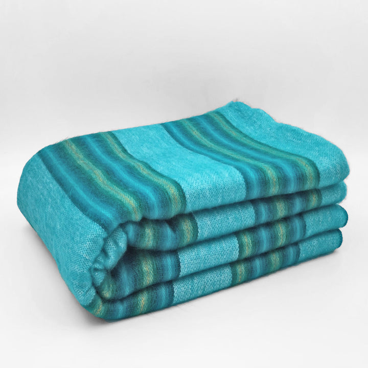 Machay baby alpaca wool blanket – a folded, turquoise-striped blanket rests neatly, showcasing its soft texture on a plain white background