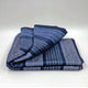 Chimborazo baby alpaca wool blanket – a folded blue and gray striped blanket rests neatly on a light, smooth surface, highlighting its textured fabric and alternating color patterns