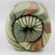 Suropata baby alpaca wool blanket – a rolled-up wool blanket displays a striped pattern with green, beige, and rust colors, set against a plain white background