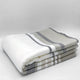 Yacoubina baby alpaca wool blanket – a neatly folded blanket with gray and beige stripes lies flat against a plain white background, emphasizing its soft texture and simple design