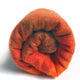 Yacupungu baby alpaca wool blanket – a rolled, vibrant orange and brown wool roving sits against a plain white background, showcasing its fluffy texture and gradient coloration