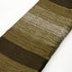 Alpaca wool queen blanket – a woolen blanket rests on a white surface, featuring horizontal stripes in various shades of green and brown, creating a textured pattern