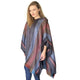 A person wearing a striped, multicolored fringed poncho stands against a plain white background. The poncho features hues of blue, red, and brown.