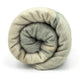 Deleg baby alpaca wool blanket – a rolled, light-colored blanket, tightly compacted, revealing layers of soft, textured fabric, set against a plain, white background