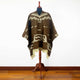 Clint Eastwood alpaca wool poncho – a brown poncho draped over a wooden mannequin stand showcases geometric patterns in a well-lit room with wooden flooring